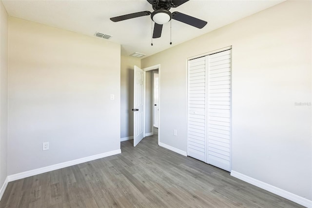 unfurnished bedroom featuring a closet, visible vents, baseboards, and wood finished floors