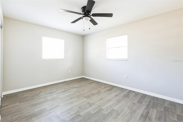 empty room featuring light wood finished floors, a ceiling fan, and baseboards