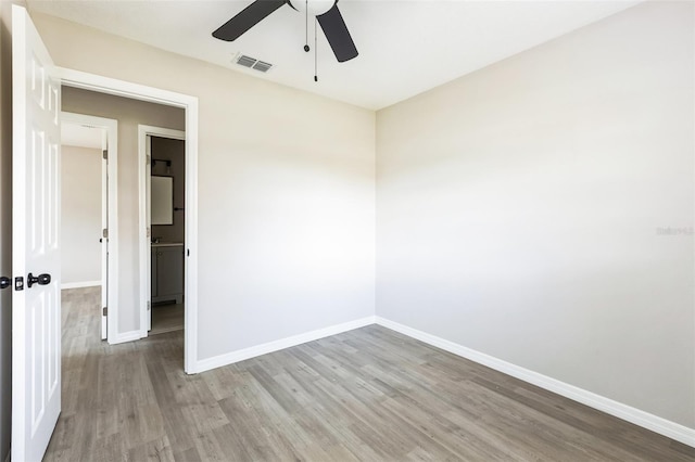 spare room with baseboards, visible vents, ceiling fan, and wood finished floors