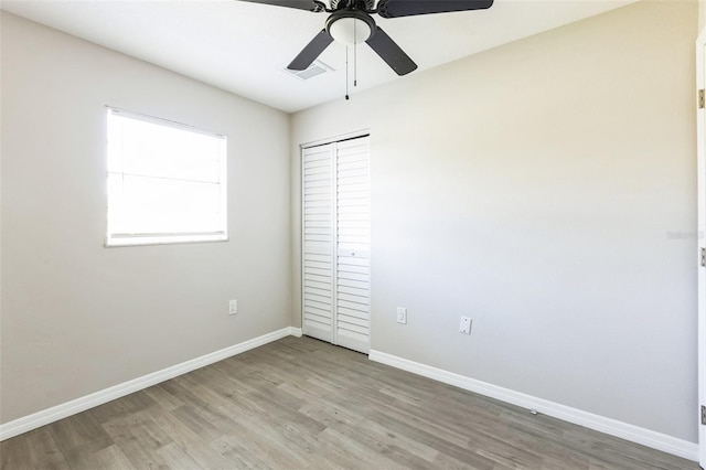 unfurnished room featuring light wood-style flooring, a ceiling fan, visible vents, and baseboards