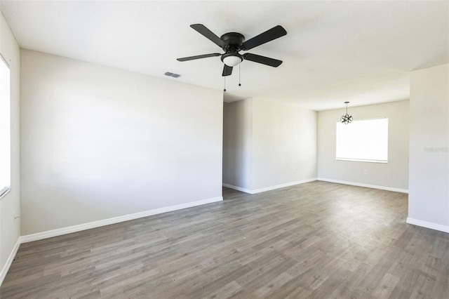 spare room featuring a ceiling fan, wood finished floors, visible vents, and baseboards