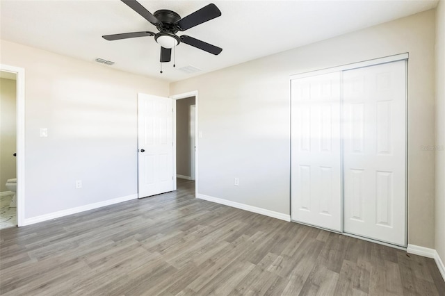 unfurnished bedroom with ceiling fan, wood finished floors, visible vents, baseboards, and a closet