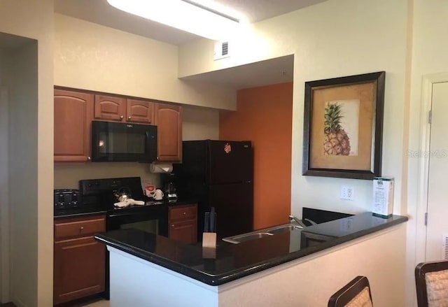 kitchen with visible vents, dark countertops, a peninsula, black appliances, and a sink