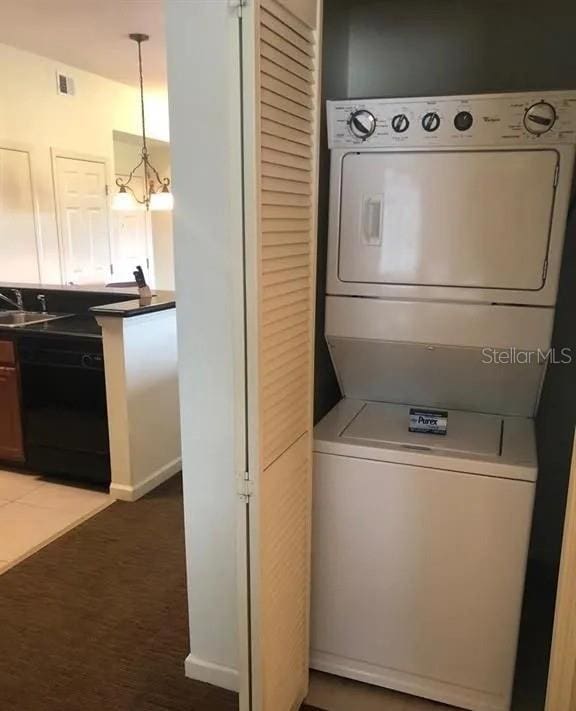 washroom with stacked washer and dryer, visible vents, laundry area, and a notable chandelier