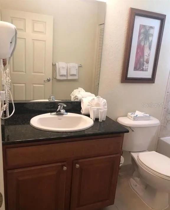 bathroom with a bathtub, vanity, and toilet