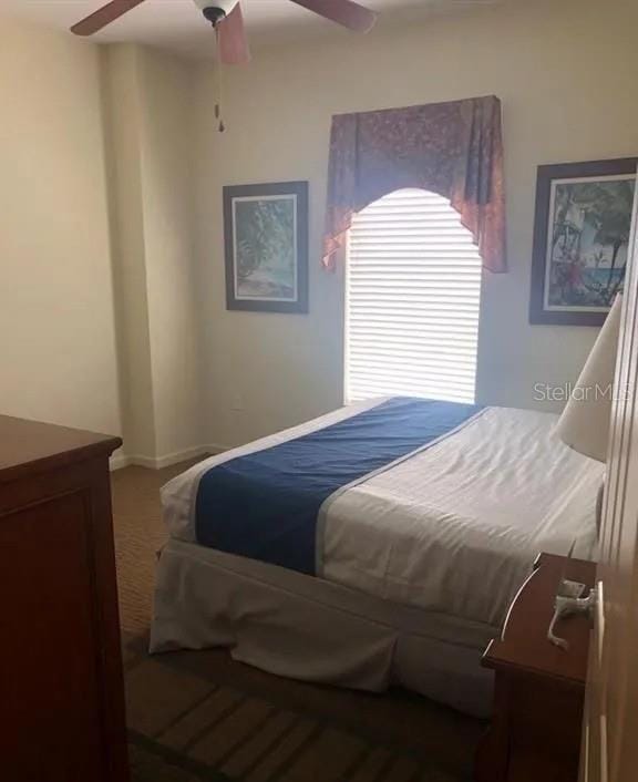 carpeted bedroom with ceiling fan and baseboards