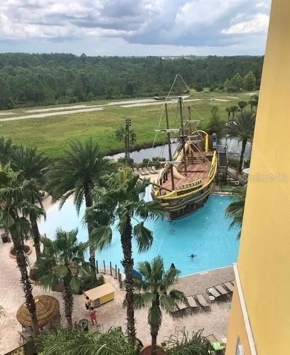 view of pool with a water view and a view of trees