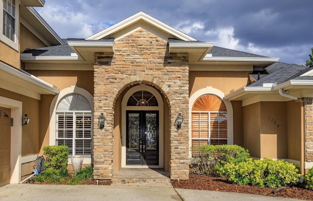 1704 Kersley Cir, Lake Mary, FL 32746 - property entrance featuring french doors, roof with shingles, stucco siding, an attached garage, and stone siding