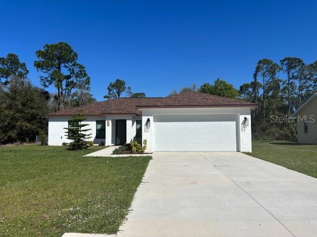 view of front of property with driveway, a front lawn, an attached garage, and stucco siding