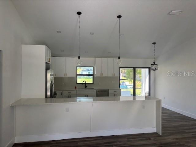 kitchen featuring light countertops, freestanding refrigerator, white cabinets, a sink, and a peninsula