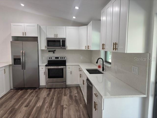 kitchen with dark wood-style floors, lofted ceiling, appliances with stainless steel finishes, white cabinetry, and a sink