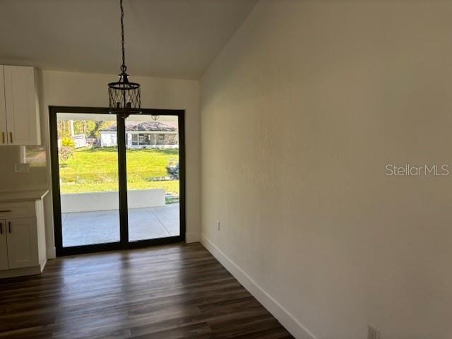 entryway with dark wood-style floors, a notable chandelier, and baseboards