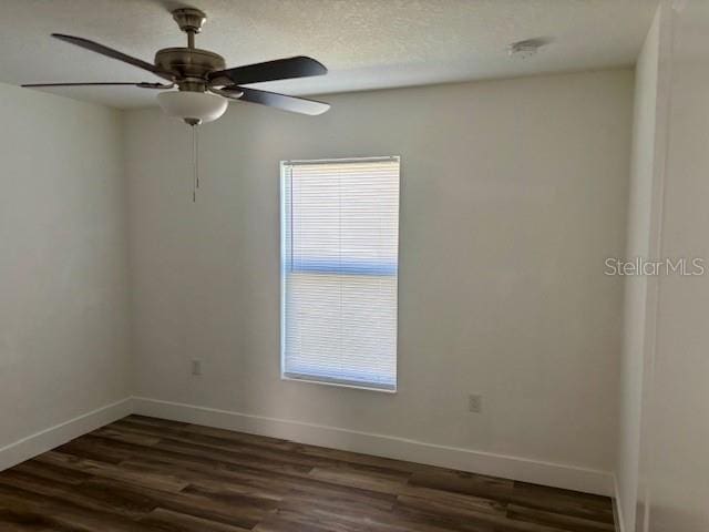 empty room with dark wood-type flooring, a textured ceiling, baseboards, and a ceiling fan