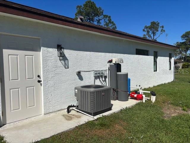 view of property exterior featuring stucco siding, a lawn, and central AC unit