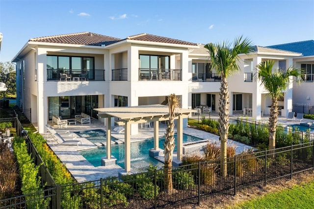 back of house with a fenced backyard, a balcony, an in ground hot tub, a fenced in pool, and stucco siding