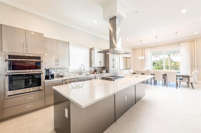 kitchen featuring tasteful backsplash, island range hood, a spacious island, appliances with stainless steel finishes, and light countertops