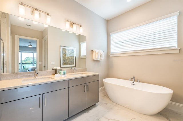 bathroom with double vanity, marble finish floor, a freestanding tub, and a sink