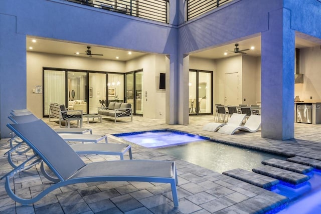 view of swimming pool featuring ceiling fan, a patio, an in ground hot tub, an outdoor living space, and exterior kitchen