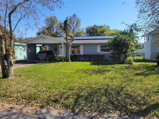 ranch-style house with a front yard, roof mounted solar panels, fence, and an attached carport