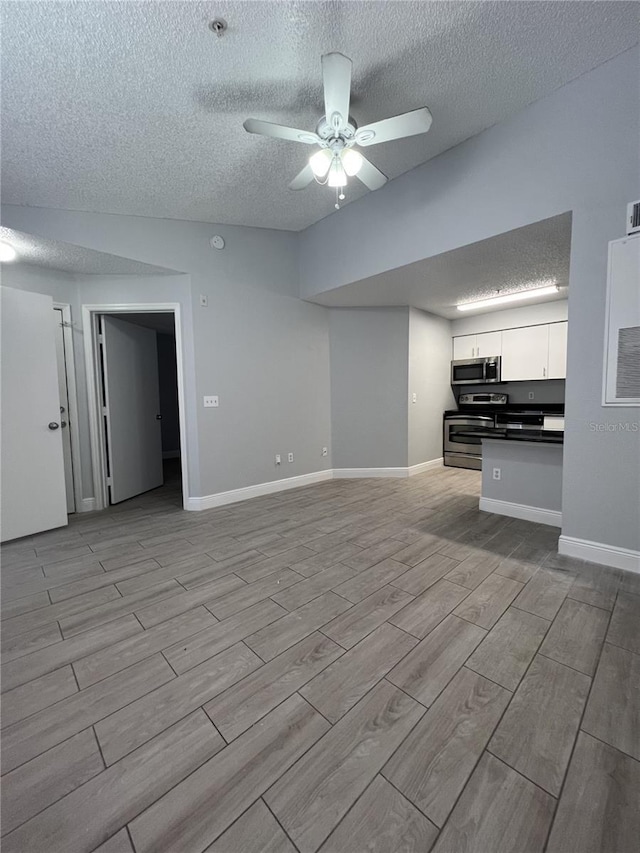 unfurnished living room featuring baseboards, a textured ceiling, a ceiling fan, and wood tiled floor