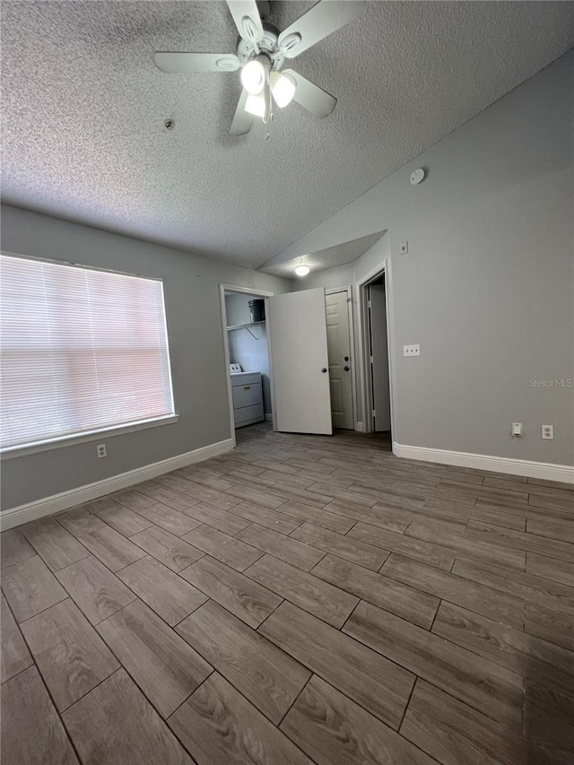 empty room with lofted ceiling, wood tiled floor, baseboards, and a textured ceiling