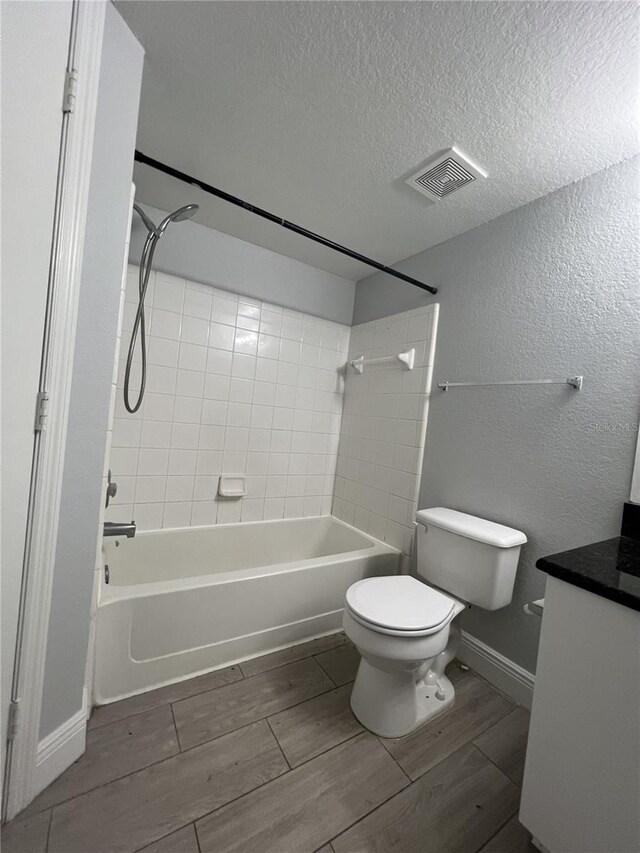 full bath featuring shower / bath combination, visible vents, toilet, a textured ceiling, and wood finish floors