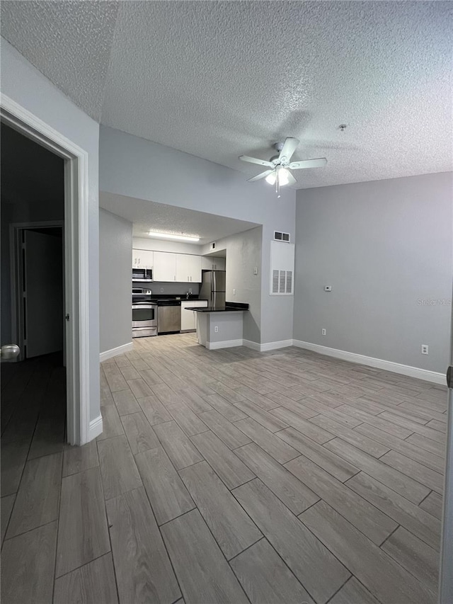 kitchen with ceiling fan, stainless steel appliances, visible vents, open floor plan, and dark countertops