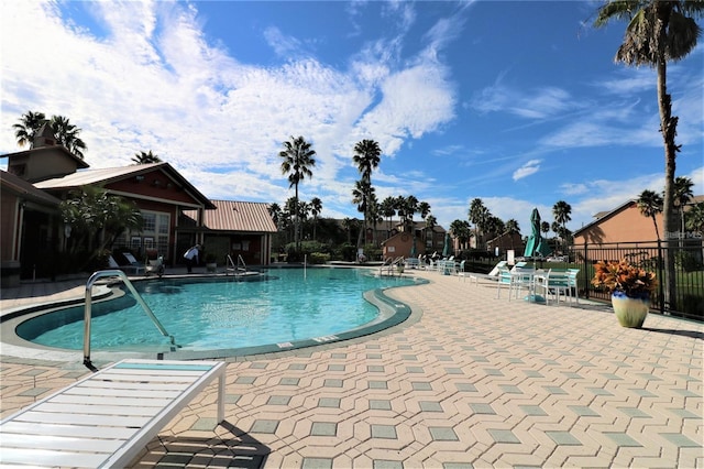 community pool with a patio area and fence