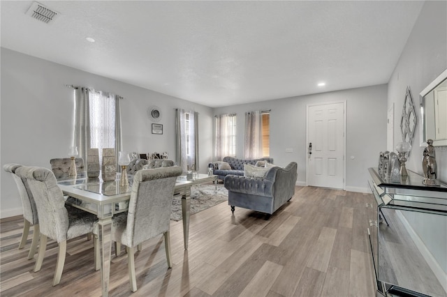 dining area with light wood-style floors, visible vents, and baseboards