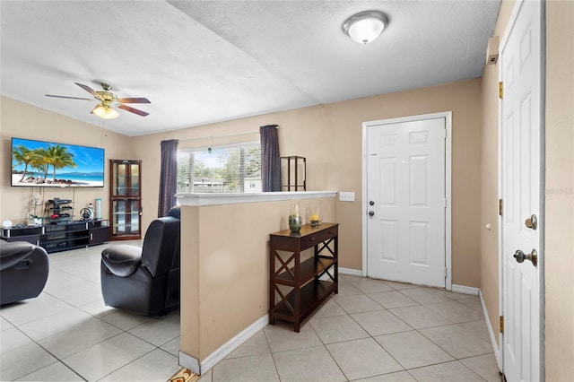 entryway featuring light tile patterned floors, a textured ceiling, a ceiling fan, and baseboards