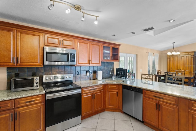 kitchen with stainless steel appliances, visible vents, vaulted ceiling, brown cabinets, and tasteful backsplash