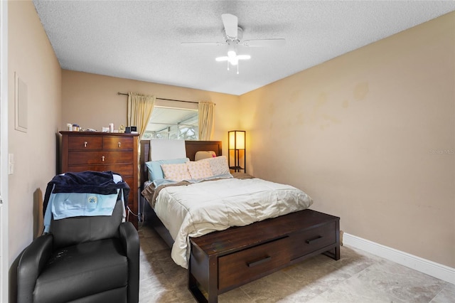 bedroom featuring a ceiling fan, a textured ceiling, and baseboards