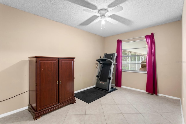 exercise area with a textured ceiling, ceiling fan, light tile patterned floors, and baseboards