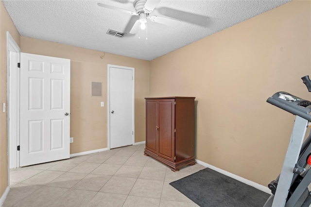 workout room with light tile patterned floors, visible vents, a ceiling fan, a textured ceiling, and baseboards