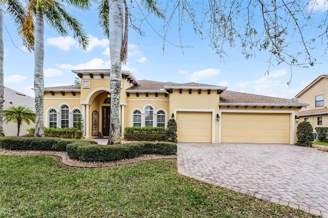 mediterranean / spanish-style house featuring a front lawn, decorative driveway, a garage, and stucco siding