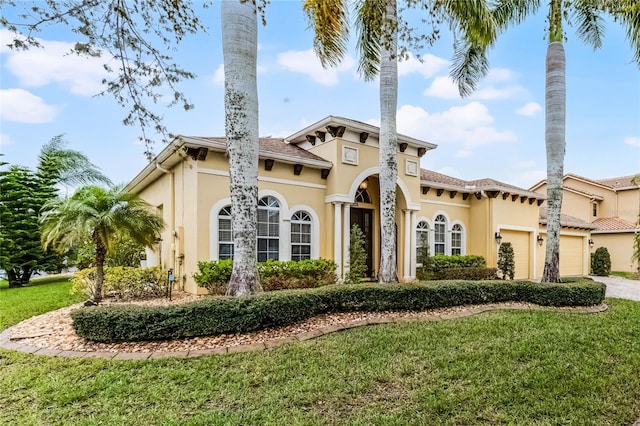 mediterranean / spanish home featuring stucco siding, an attached garage, and a front lawn