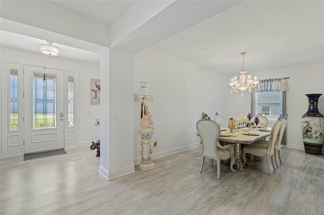 dining space featuring baseboards, a chandelier, and wood finished floors