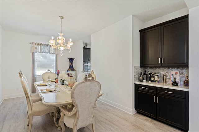 dining room with baseboards, light wood-type flooring, and an inviting chandelier