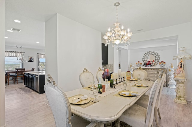 dining room with light wood finished floors, recessed lighting, visible vents, and an inviting chandelier