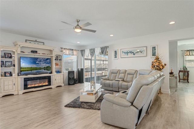 living room featuring recessed lighting, a ceiling fan, wood finished floors, and a glass covered fireplace