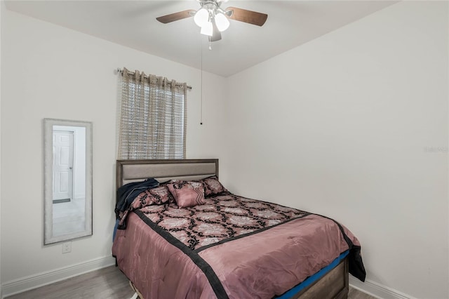 bedroom with a ceiling fan, baseboards, and wood finished floors