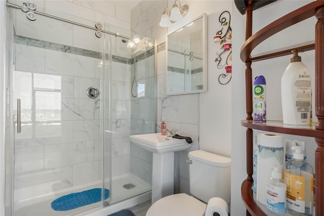 full bath with tile walls, a sink, a shower stall, and toilet