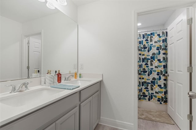 full bathroom with double vanity, shower / bathtub combination with curtain, baseboards, and a sink