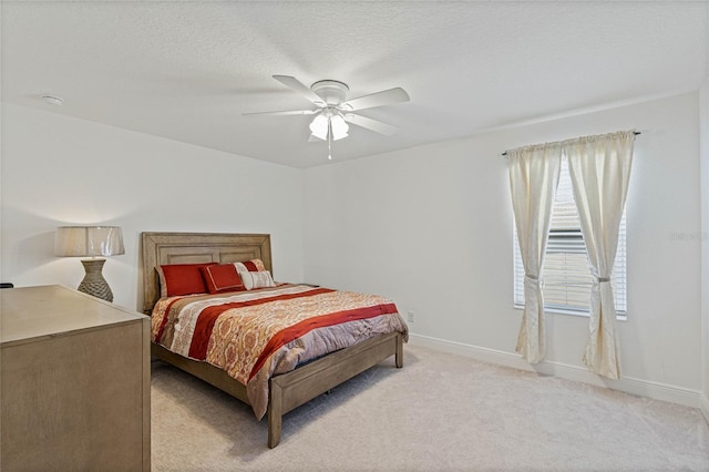 bedroom featuring light carpet, a textured ceiling, a ceiling fan, and baseboards