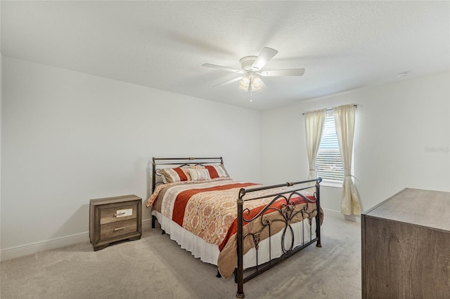 bedroom featuring light carpet, ceiling fan, baseboards, and a textured ceiling