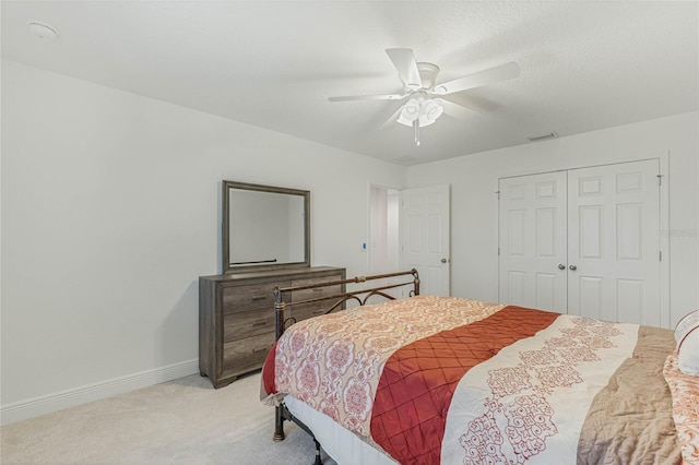 bedroom with a closet, visible vents, light carpet, ceiling fan, and baseboards