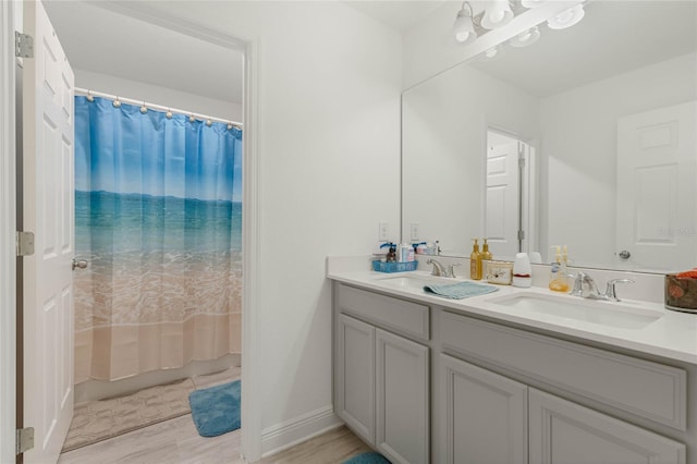 full bath with double vanity, shower / bath combo, baseboards, and a sink