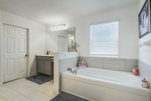 full bath with a garden tub, a textured ceiling, and vanity