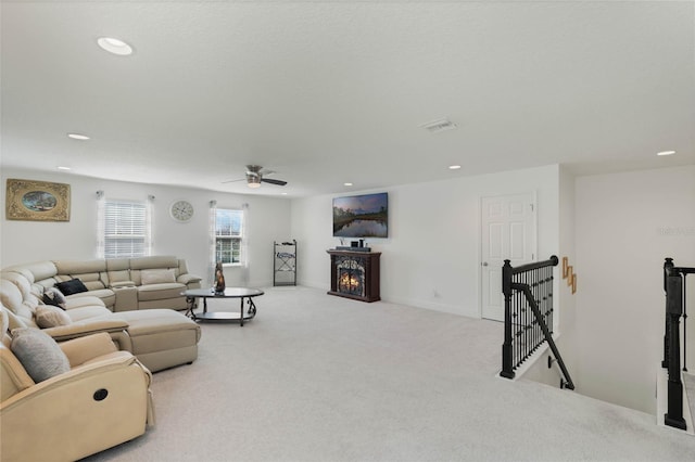 living room featuring recessed lighting, carpet flooring, visible vents, baseboards, and a lit fireplace