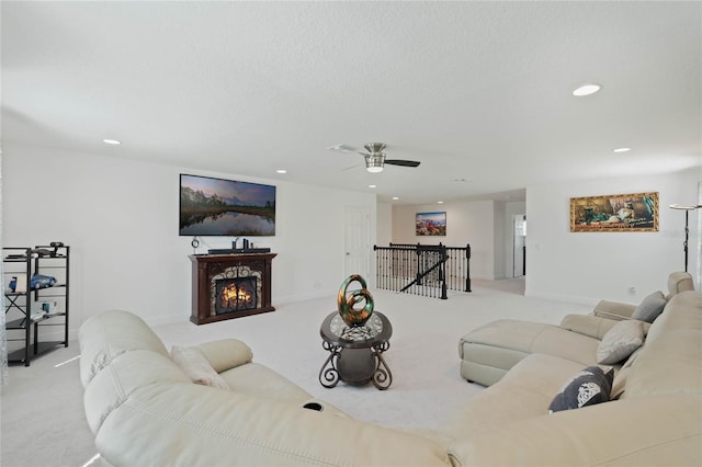 carpeted living room featuring a lit fireplace, baseboards, a textured ceiling, and recessed lighting